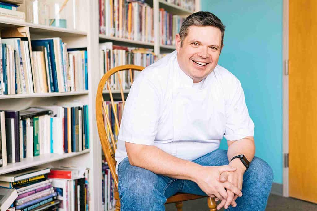 Chef Chad Kelley sittng in front of a wall of books